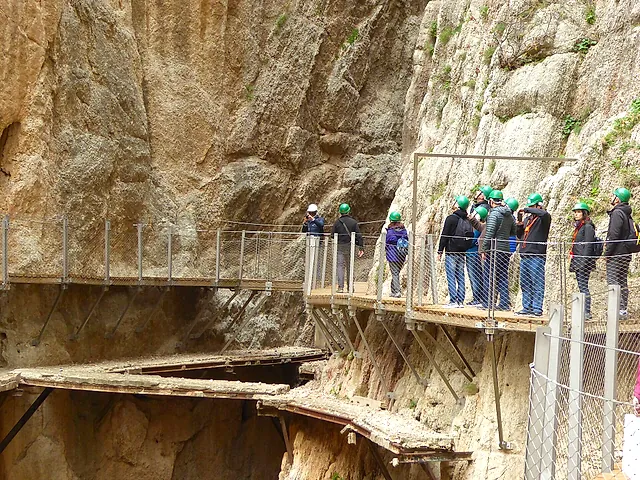 Visitors in helmets on the boardwalks high on the canyon wall